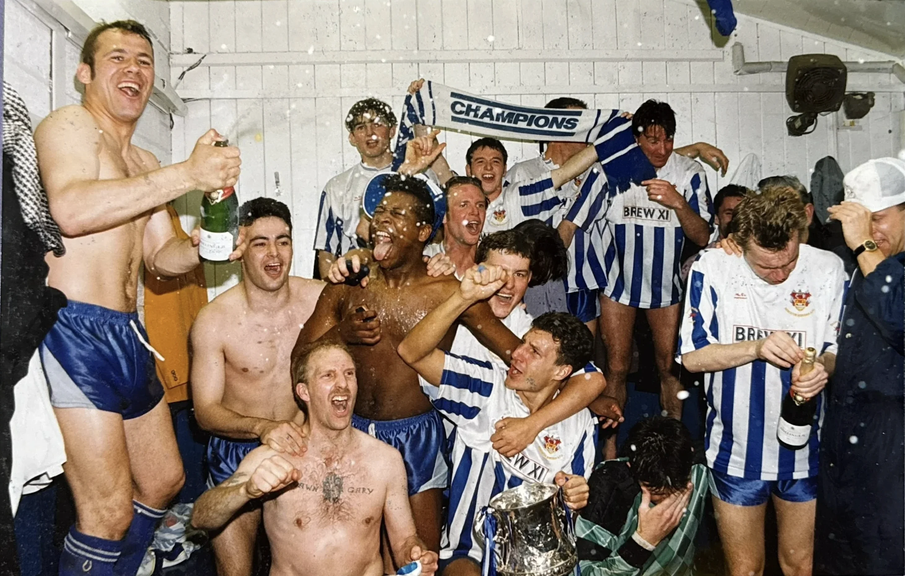 Nuneaton Borough players celebrate with the championship trophy in the dressing room